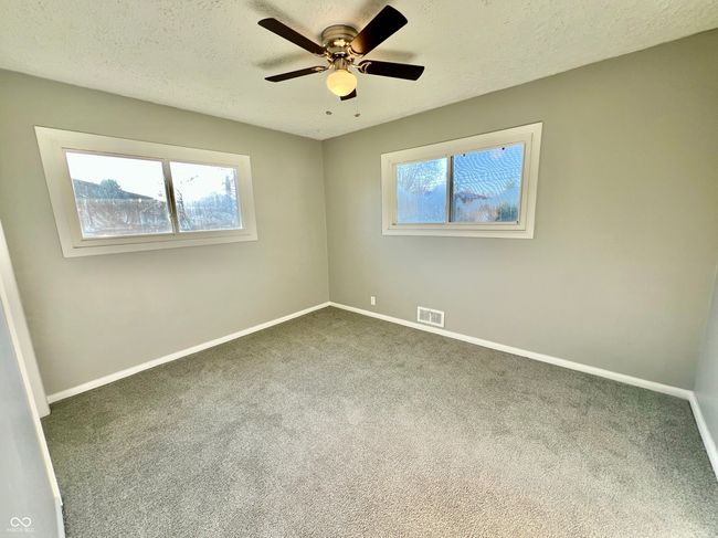 carpeted spare room featuring visible vents, baseboards, a textured ceiling, and ceiling fan | Image 17