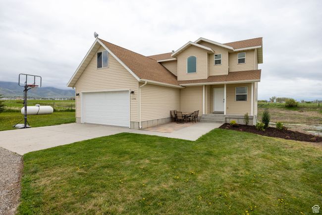 View of front of property with a shingled roof, concrete driveway, a front lawn, and a mountain view | Image 25
