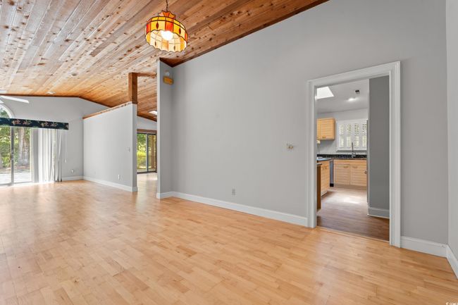 Unfurnished living room with healthy amount of natural light, light wood-style floors, lofted ceiling, and wooden ceiling | Image 15