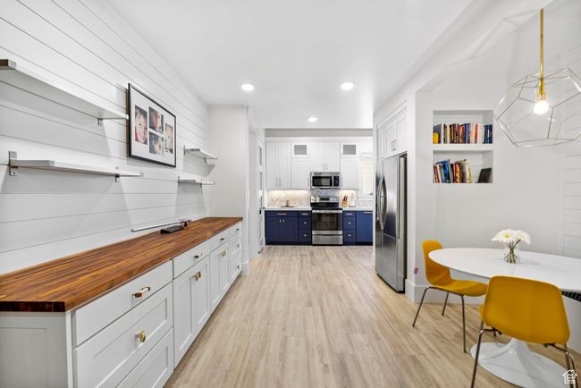 Kitchen with open shelves, appliances with stainless steel finishes, wood counters, light wood-style flooring, and blue cabinets | Image 67