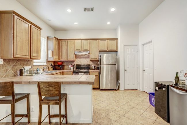 Kitchen with freestanding refrigerator, black gas range, a peninsula, decorative backsplash, and a breakfast bar area | Image 7