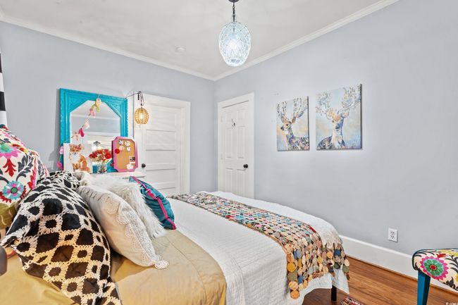 Bedroom with wood finished floors and crown molding | Image 23