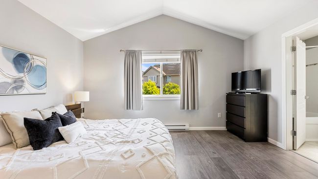 Bedroom with lofted ceiling, baseboards, baseboard heating, and wood finished floors | Image 16