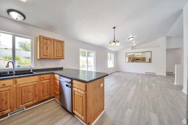 Kitchen with dishwasher, a sink, light LVP flooring, vaulted ceiling, and a chandelier | Image 9