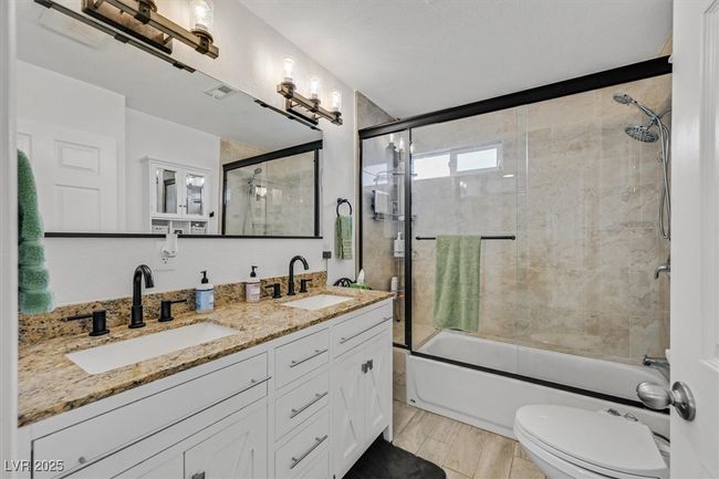 Bathroom with enclosed tub / shower combo, double vanity, toilet, and a sink | Image 23