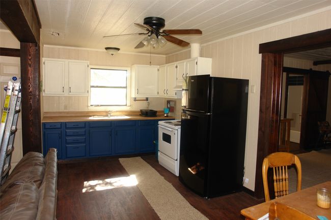 Kitchen featuring white electric range, blue cabinets, sink, black fridge, and white cabinets | Image 15