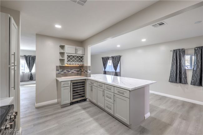 Kitchen with a peninsula, wine cooler, open shelves, and gray cabinetry | Image 14