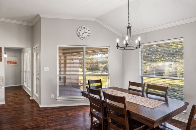 Dining room with vaulted ceiling, an inviting chandelier, dark wood-type flooring, and a healthy amount of sunlight | Image 10