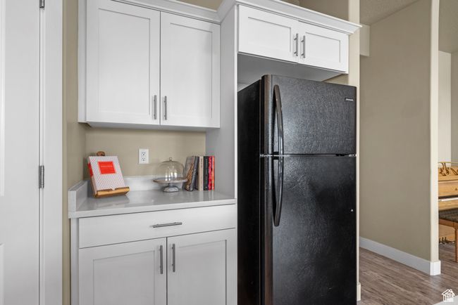 Kitchen with light countertops, white cabinets, freestanding refrigerator, and wood finished floors | Image 12