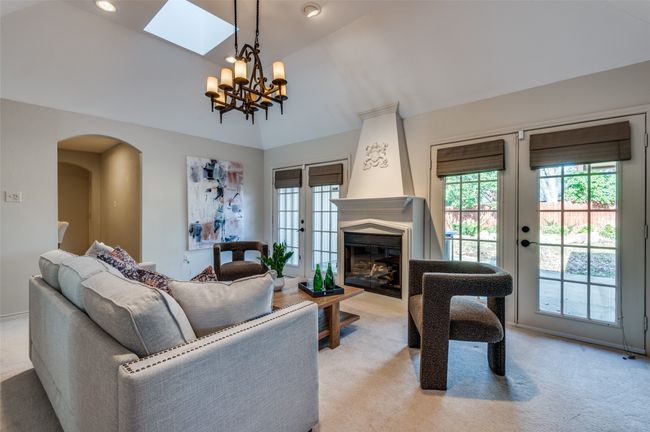 Living area with arched walkways, light colored carpet, vaulted ceiling, french doors, and a fireplace | Image 18