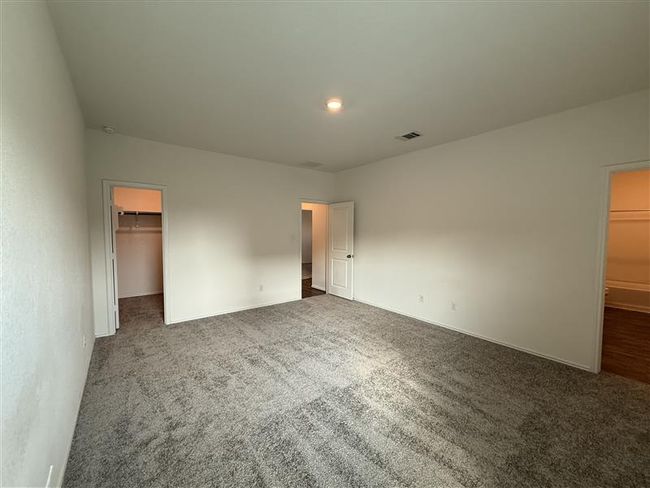 Unfurnished bedroom with a walk in closet, carpet floors, a closet, and baseboards | Image 14