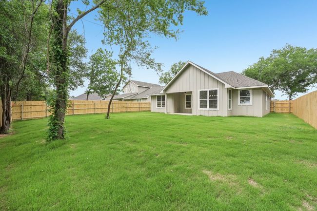 Back of house with board and batten siding, a lawn, a shingled roof, and a fenced backyard | Image 37