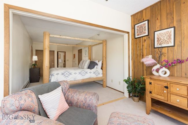 Carpeted bedroom with a baseboard heating unit and wooden walls | Image 12