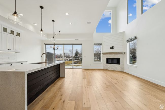 Kitchen with light wood finished floors, a sink, white cabinets, open floor plan, and backsplash | Image 6