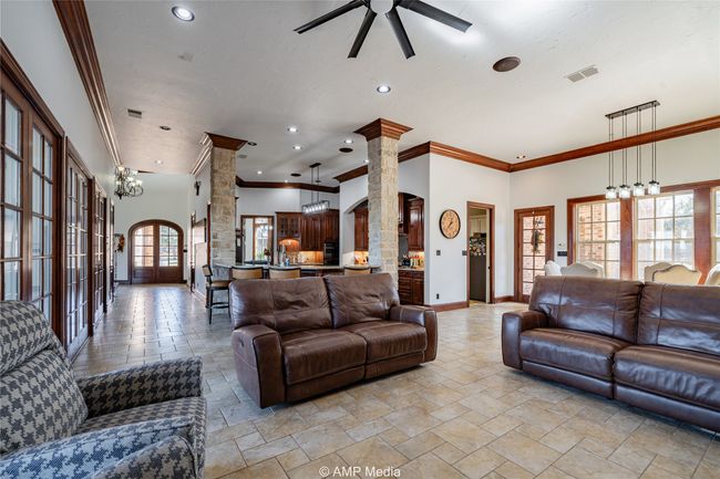 Living room featuring ceiling fan with notable chandelier, ornate columns, ornamental molding, and a towering ceiling | Image 10