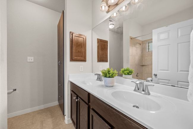 Bathroom featuring double vanity, baseboards, a shower, and tile patterned floors | Image 18
