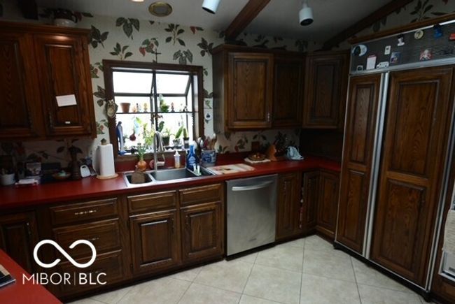 kitchen with lofted ceiling, light tile patterned floors, a sink, wallpapered walls, and dishwasher | Image 13