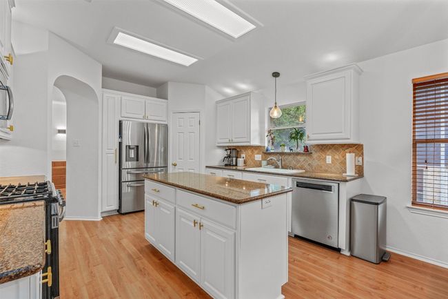 Kitchen featuring appliances with stainless steel finishes, arched walkways, light wood finished floors, and decorative backsplash | Image 11