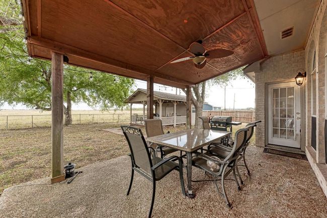 Fenced backyard with a ceiling fan, outdoor dining space, and a patio | Image 31