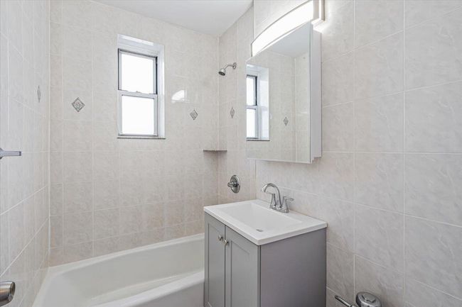 Bathroom featuring vanity, tile walls, and tiled shower / bath | Image 10