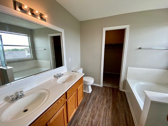 Bathroom featuring a bath, wood finished floors, double vanity, and a walk in closet | Image 22