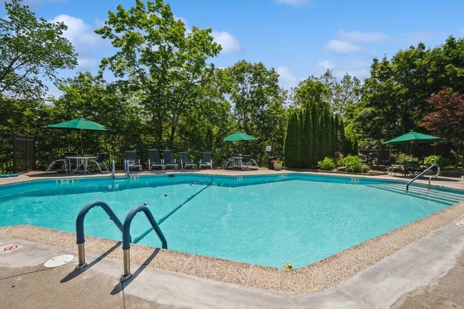 Community pool featuring a patio area and view of wooded area | Image 19