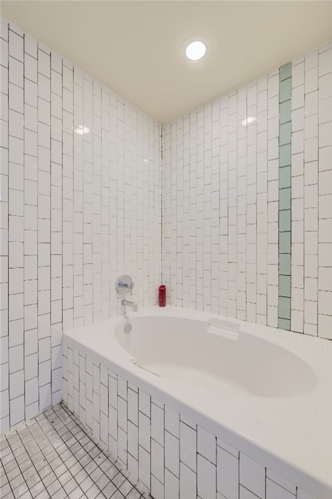 Full bathroom with a relaxing tiled tub, tile patterned floors, and tile walls | Image 20