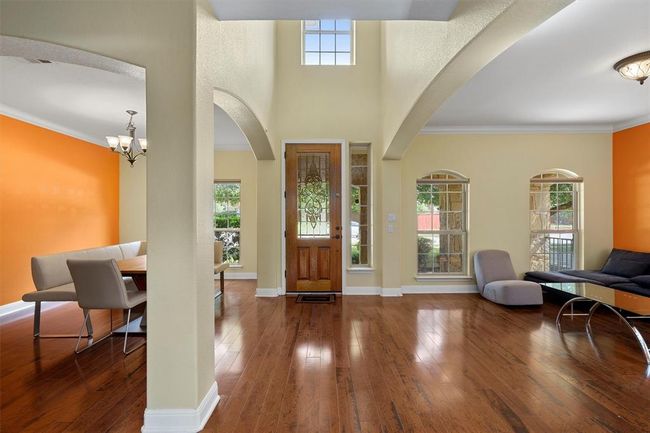 Foyer with wood-type flooring, arched walkways, a chandelier, crown molding, and baseboards | Image 5