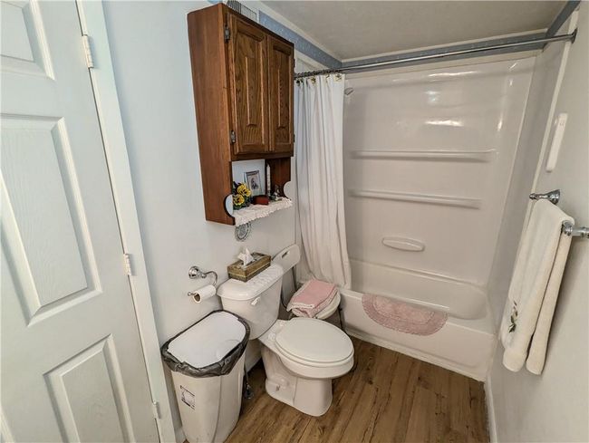Bathroom with wood finished floors, shower / tub combo, and toilet | Image 27