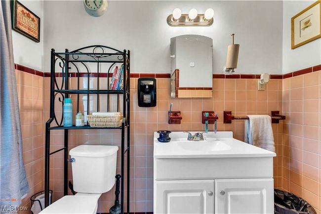 Bathroom with tile walls, vanity, toilet, and a wainscoted wall | Image 21