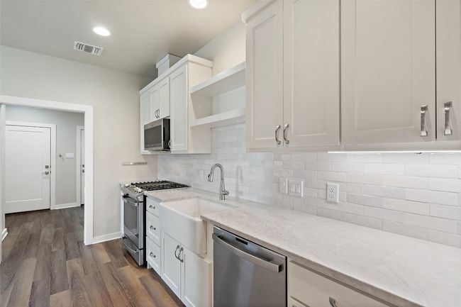 Kitchen featuring stainless steel appliances, open shelves, a sink, white cabinets, and recessed lighting | Image 33