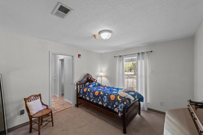 Bedroom featuring light colored carpet, visible vents, baseboards, and a textured ceiling | Image 22