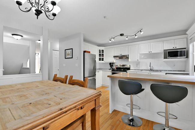 Kitchen with glass insert cabinets, tasteful backsplash, appliances with stainless steel finishes, under cabinet range hood, and butcher block countertops | Image 10