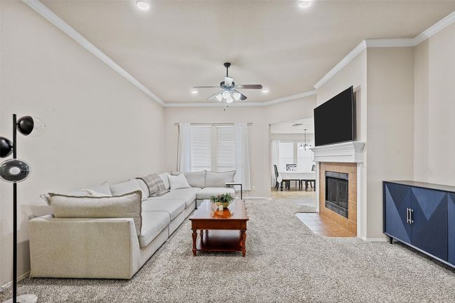 Living area with a ceiling fan, a tiled fireplace, carpet, crown molding, and recessed lighting | Image 10