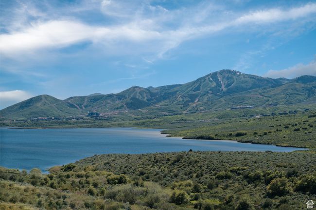 View of mountain backdrop with a nearby body of water and a forest | Image 40
