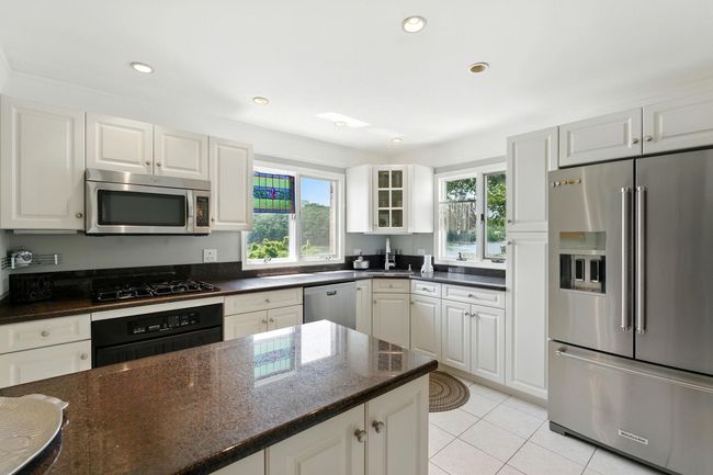 Kitchen featuring appliances with stainless steel finishes, healthy amount of natural light, glass insert cabinets, white cabinets, and recessed lighting | Image 19