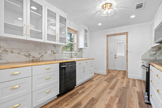 Kitchen featuring stainless steel electric range oven, visible vents, dishwasher, light wood-style floors, and backsplash | Image 20