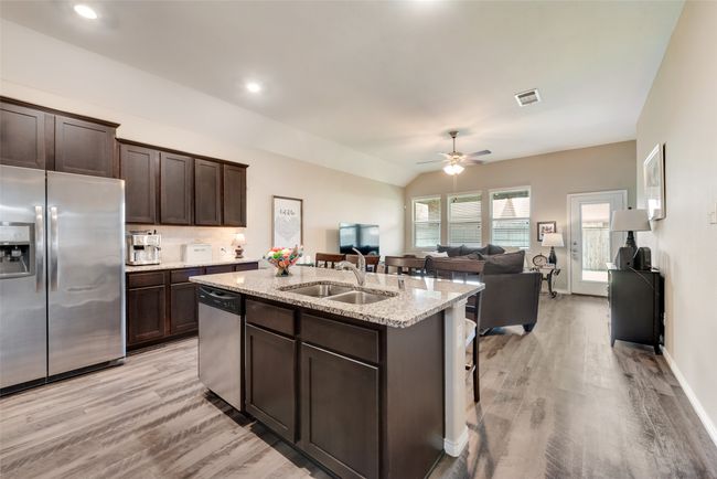 Kitchen featuring appliances with stainless steel finishes, light wood-style flooring, open floor plan, an island with sink, and dark brown cabinets | Image 10