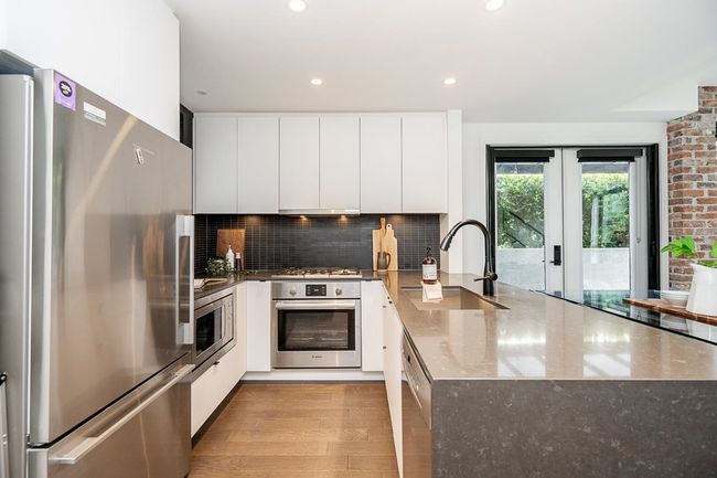 Kitchen with modern cabinets, appliances with stainless steel finishes, a peninsula, french doors, and white cabinets | Image 5