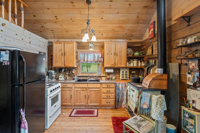 Kitchen featuring a wood burning cook stove and new gas range | Image 9