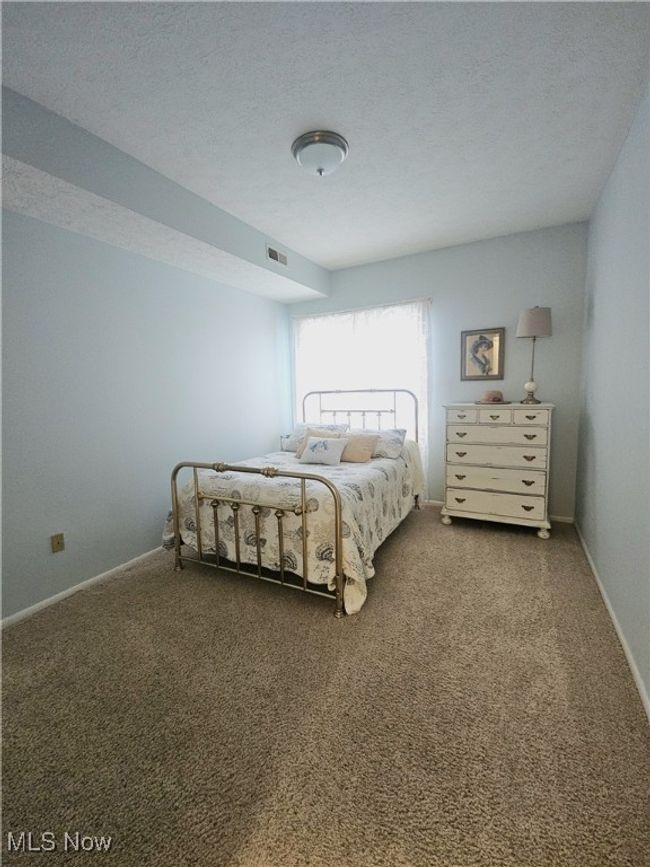Bedroom with a textured ceiling and carpet | Image 10