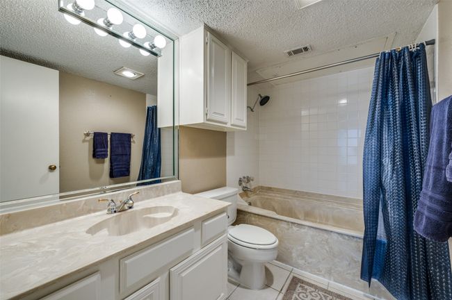 Full bathroom with vanity, shower / tub combo, toilet, tile patterned floors, and a textured ceiling | Image 11