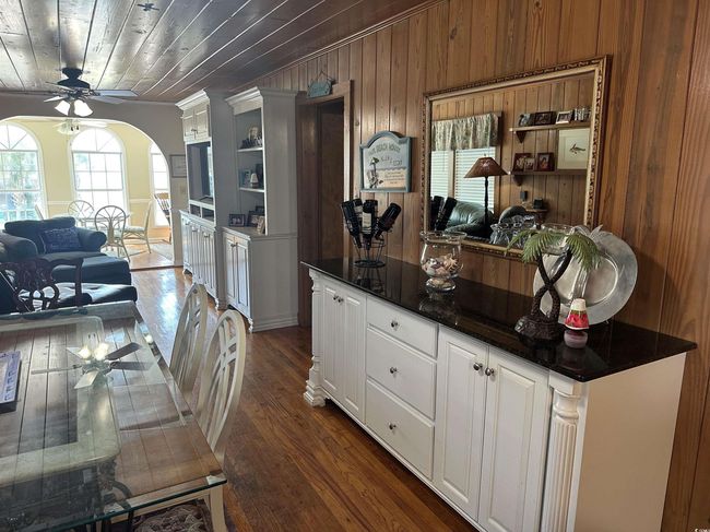 Kitchen with ceiling fan, dark countertops, arched walkways, dark wood-style flooring, and white cabinetry | Image 9