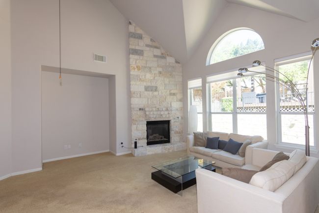Living area featuring high vaulted ceiling, a fireplace, visible vents, carpet flooring, and baseboards | Image 10