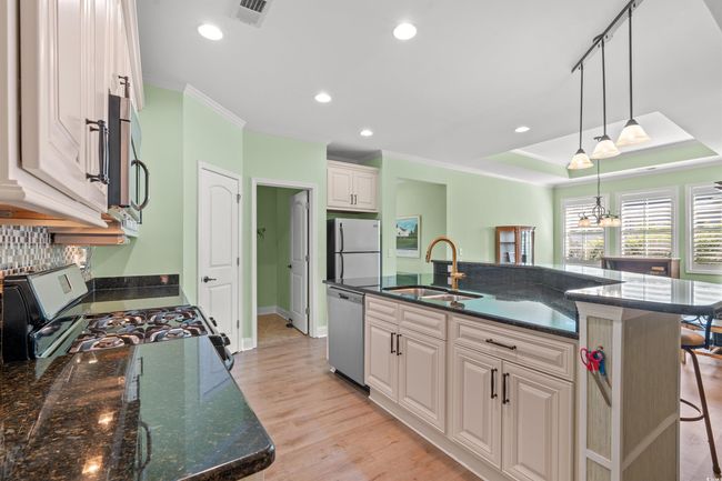 Kitchen featuring white cabinetry, a sink, light wood finished floors, visible vents, and appliances with stainless steel finishes | Image 10