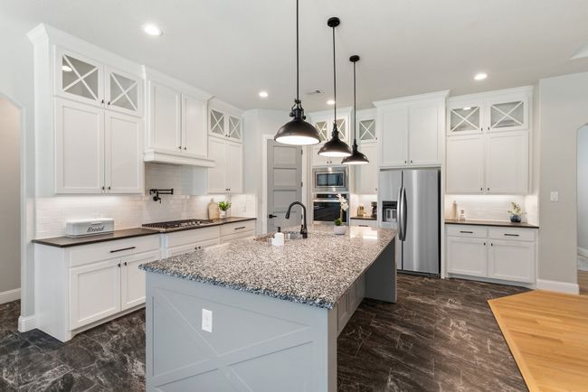 Kitchen featuring backsplash, glass insert cabinets, appliances with stainless steel finishes, and a sink | Image 10