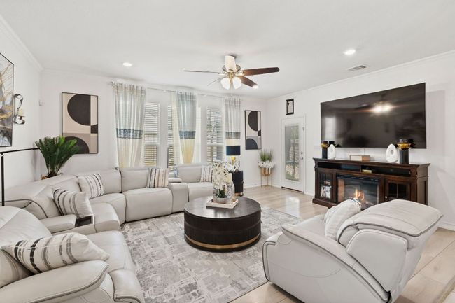 Living room featuring ceiling fan, ornamental molding, light wood-type flooring, recessed lighting, and a glass covered fireplace | Image 14