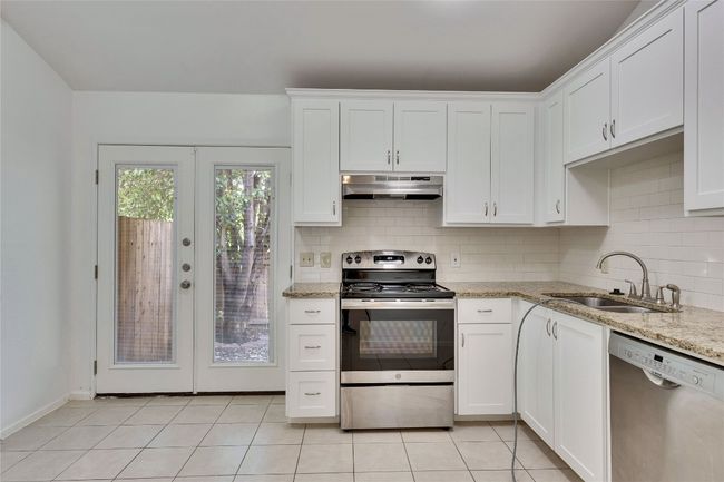 Kitchen featuring stainless steel appliances, french doors, decorative backsplash, and white cabinetry | Image 10