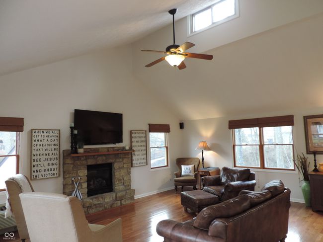 living room featuring a stone fireplace, a healthy amount of sunlight, and wood finished floors | Image 10
