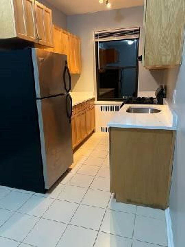 Kitchen with light countertops, freestanding refrigerator, a sink, and light tile patterned floors | Image 26